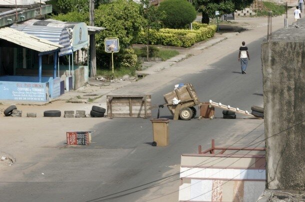 A man walks near a road block in Abidjan