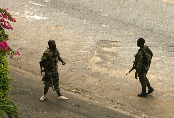 Pro-Gbagbo soldiers with their weapons walk in a street around the presidential palace, which is under their control, in Abidjan