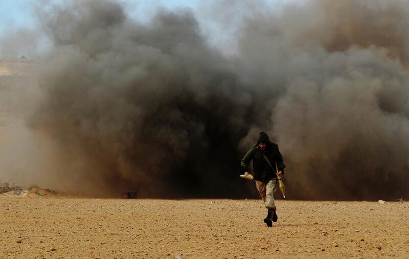 A Libyan rebel fighter run for cover as