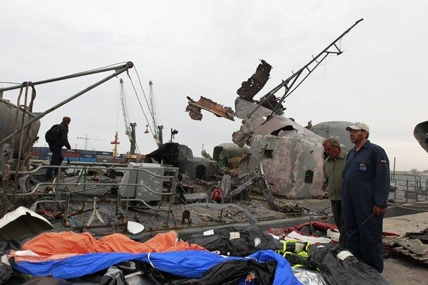 A worker walks near damaged warships at the sea port in Tripoli
